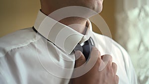 a man puts on a tie