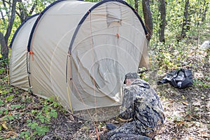 A man puts up a tent on the site of a future camp in the forest