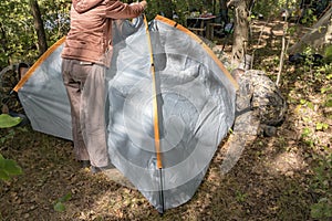 A man puts up a tent on the site of a future camp in the forest