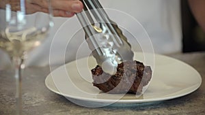 A man puts a white plate and a wine glass on the table