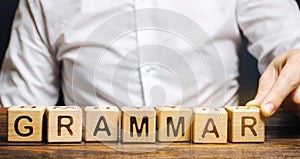 A man puts wooden blocks with the word Grammar. Set of structural rules governing the composition of clauses, phrases and words in photo
