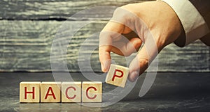 A man puts wooden blocks with the word HACCP. Hazard analysis and critical control points. Quality management rules for food