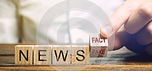A man puts wooden blocks with the words News - Fact or fake. False / true information concept. Yellow press