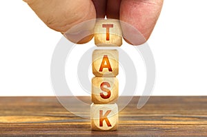 A man puts wooden cubes on the table with the inscription - TASK