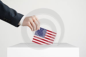 Man putting a ballot with American flag into a voting box