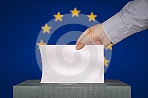 man putting ballot in a box during elections in european union against background of the European flag