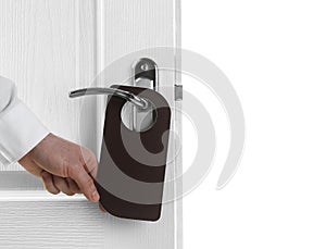 Man putting blank hanger on hotel door handle against white background, closeup