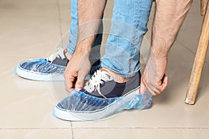 Man putting on blue shoe covers