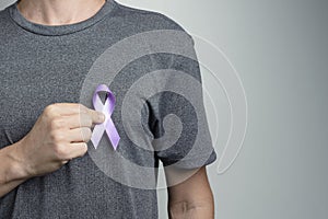 Man putting blue violet ribbon on shirt. Awareness symbol