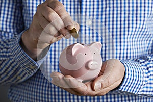 Man Putting Coin Into Piggy Bank