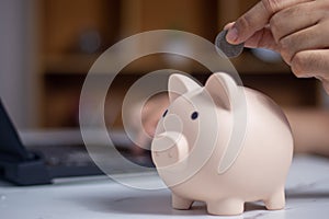 man putting coin in piggy bank and press the calculator with coins placed on the account book money saving concept