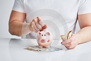 Man putting coin into piggy bank