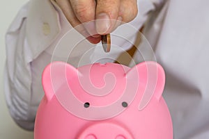 Man is putting coin in piggy money bank