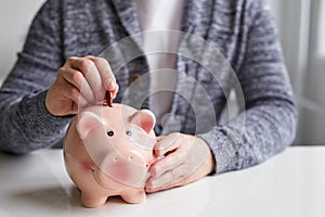 Man putting coin into small piggy bank