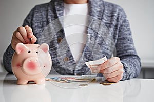 Man putting coin into small piggy bank