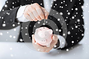 Man putting coin into small piggy bank