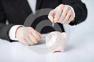 Man putting coin into small piggy bank