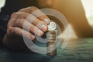 Man putting a coin with the word liberty on a money stack. Finance, banking, savings, personal budget, liberalism, increase in