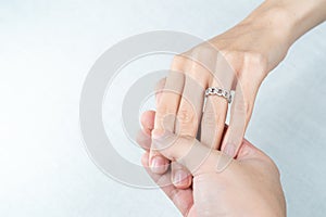 Man putting diamond ring on woman hand over white background