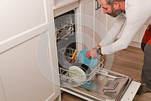 man putting dishes in the dishwasher