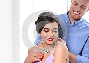 Man putting elegant jewelry on beautiful woman