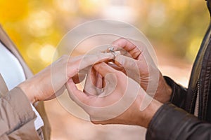 Man putting engagement ring on woman`s hand outdoors