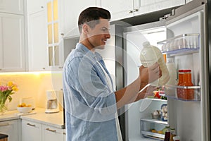 Man putting gallon of milk into refrigerator in kitchen