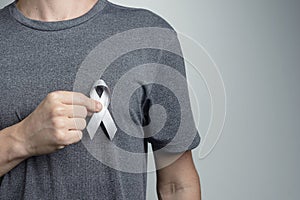 Man putting gray ribbon on his shirt. Awareness symbol