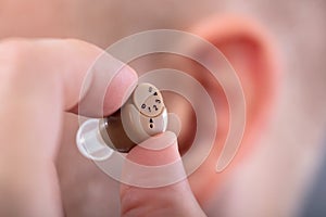 Man Putting Hearing Aid In His Ear