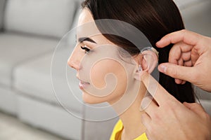 Man putting hearing aid in woman`s ear, closeup