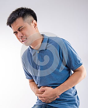 Man putting his hands for belly or stomach ache on white background