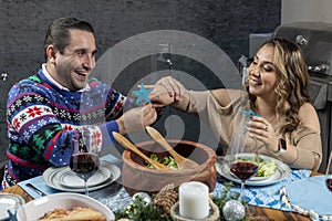 man putting his wife a christmas decoration ring at christmas dinner