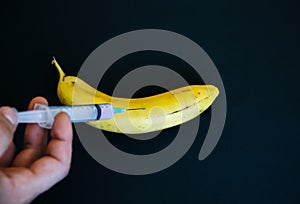 Man is putting injection in banana. GMP productos. Fruit with pesticide photo