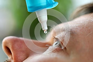 Man putting liquid drops in his eye solving vision problem