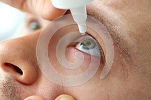 Man putting liquid drops in his eye solving vision problem