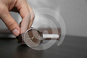 Man putting luxury wrist watch on table, closeup. Space for text