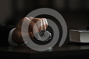 Man putting luxury wrist watch on table, closeup. Space for text