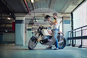 Man putting on motorcycle helmet in a garage