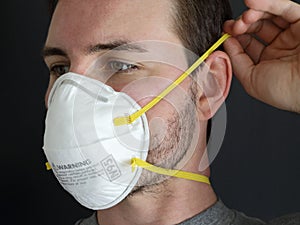 Man Putting on an N95 Protective Dust Mask Up Close