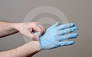 Man putting on a pair of latex gloves