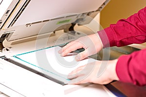 Man putting paper sheet on printer for scanning. Office work concept.