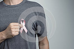 Man putting pink ribbon on his shirt. Awareness symbol
