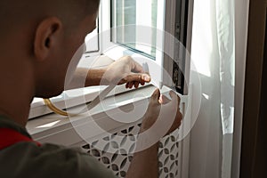 Man putting rubber draught strip onto window, closeup