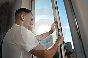 Man putting rubber draught strip onto window indoors