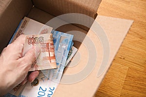 A man putting russian ruble banknotes into a cardboard box