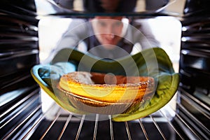 Man Putting Savoury Pie Into Oven To Bake