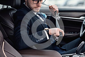 Man Putting On Seat Belt Sitting In Luxury Car
