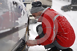 Uomo introduzione la neve catene sul auto pneumatico 