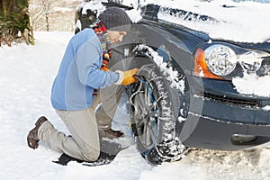 Man Putting Snow Chains Onto Tyre Of Car