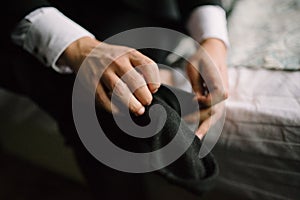 Man putting socks on his feet close-up in bedroom